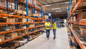 two-warehouse-workers-walking-distribution-storage-area-discussing-about-logistics-organization_342744-1456